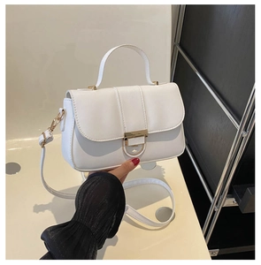 Detail of white PU leather crossbody bag featuring gold buckle and elegant top handle