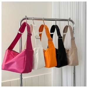 Detailed view of minimalist crossbody bags in five colors hanging on a metal rack
