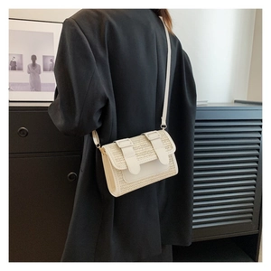 Detail of cream woven crossbody bag with leather straps on model in black blazer