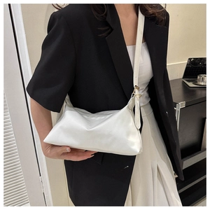 Close-up of a white minimalist cloud bag with soft pleats and gold hardware detail