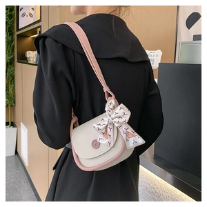 Detail of crossbody saddle bag featuring contrast piping and decorative printed silk scarf