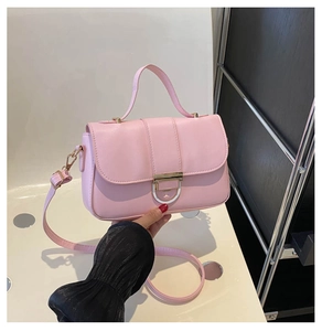 Detail view of pink leather handbag showing golden lock with white ring and shoulder strap