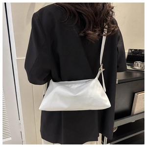 Rear view of model wearing a minimalist white PU leather shoulder bag with black blazer