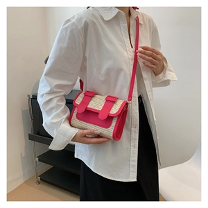 Detail of a mini woven crossbody bag featuring pink leather trim and natural straw texture