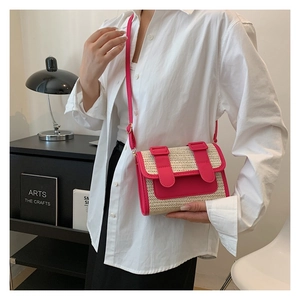 Detail of pink faux leather strap and beige straw texture on a crossbody bag