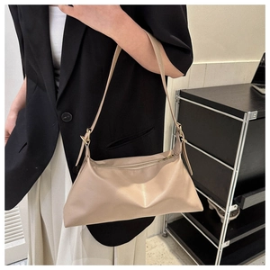 Detail of minimalist beige PU leather shoulder bag with gold hardware and soft pleats
