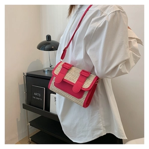 Close-up of straw woven crossbody bag with vibrant magenta PU leather trim on model