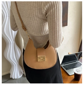 Close-up of camel faux leather saddle bag with golden metallic clasp and thin strap