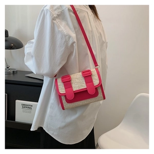 Detail of pink faux leather trim and straw woven texture on a stylish satchel bag