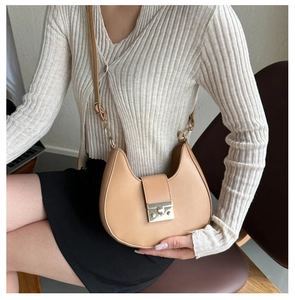 Close-up of saddle bag with adjustable strap worn by model in minimalist indoor setting