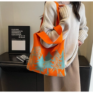 Macro detail of high-quality orange knitted tote bag with light blue pine tree pattern