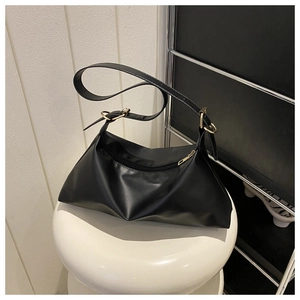 Detail of soft black PU leather shoulder bag with glossy finish and gold metal ring buckle
