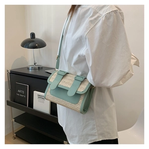 Detail showing mint green leather trim and woven straw texture on a crossbody bag