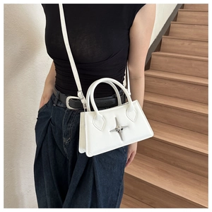 Close-up of white PU leather crossbody bag with silver star emblem on a wooden staircase