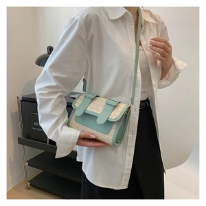 Detail of woven straw handbag with light blue leather strap and vintage buckle closure