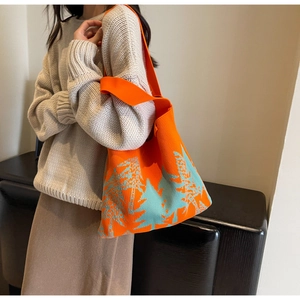 Detail of orange knitted tote bag with blue pine trees and textured shoulder strap