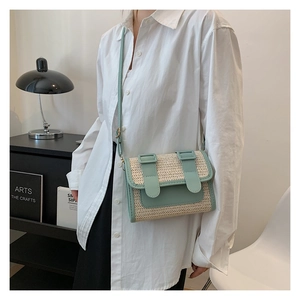 Detail of straw woven crossbody bag with light green leather trim on a female model