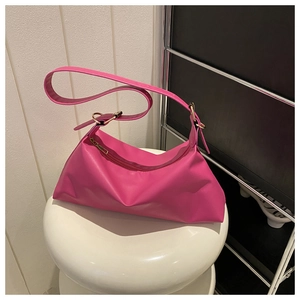 Detail of rose red PU leather shoulder bag with gold metal buckle on a white stool