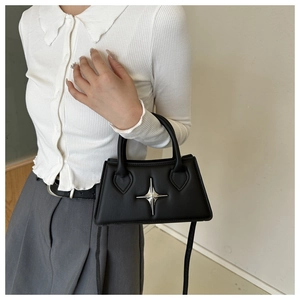 Detailed view of black matte leather handbag with a silver star ornament and shoulder strap