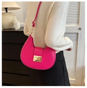 Detail of fuchsia crescent moon bag with gold lock and adjustable strap on a model
