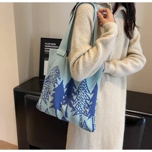 Detail of light blue knit tote bag with dark blue pine landscape pattern on shoulder