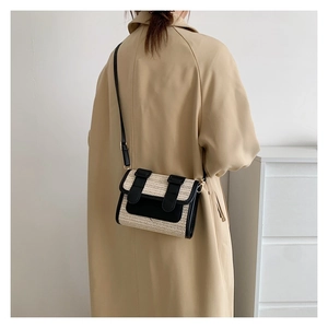 Detail of a color-block straw crossbody bag paired with a beige trench coat for a chic look