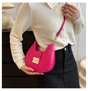 Detailed close-up of rose red saddle bag with gold metal buckle and leather strap