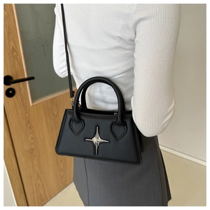 Detail of chic black faux leather handbag with silver star ornament and shoulder strap
