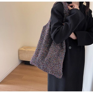 Close-up of a multicolor knit shoulder bag with metallic thread texture on model