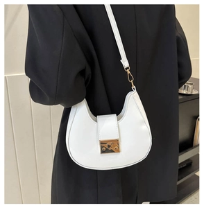 Close-up of a white crescent saddle bag with gold metal buckle and leather strap