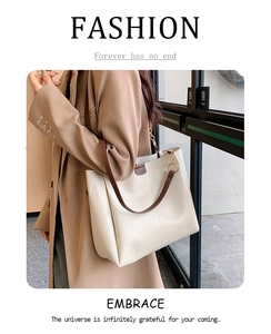 Minimalist beige tote bag with slim brown leather straps shown in a high-end street style