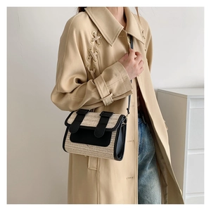 Detail of beige straw woven crossbody bag with black leather straps on a model
