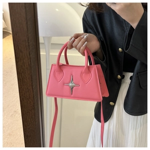 Close-up of pink crossbody bag with silver star detail held in hand for size context