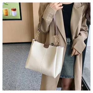 Detail of off-white tote bag featuring gold ring accents and slim brown shoulder straps