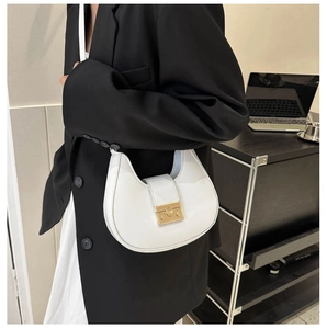 Close-up of a white crescent moon underarm bag with gold buckle on a black blazer