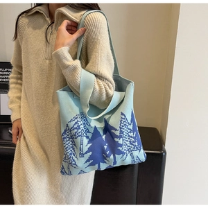 Close-up of light blue knitted tote bag featuring dark blue pine tree jacquard pattern