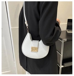 Detail of white half-moon saddle bag with gold metal buckle on female model in black suit