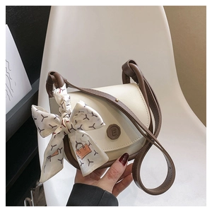 Detail of cream and mocha crossbody bag with decorative silk scarf and round 'E' plaque