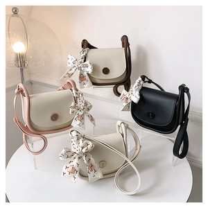 Detail of four stylish square handbags with ribbon bows and E-shaped magnetic clasps