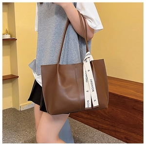 Close-up of brown soft leather tote bag with long straps and fashion ribbon detail