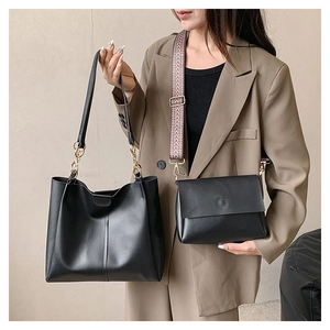 Detail of black leather tote and crossbody bag with a patterned wide strap on a model