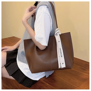 Detail of dark brown tote bag featuring fine double stitching and printed silk ribbon