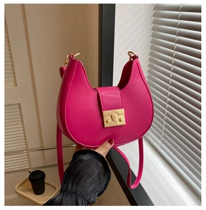 Detail of rose pink crescent saddle bag with gold metal buckle and leather texture