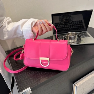 Hot pink leather crossbody bag with golden D-ring hardware in a stylish office setting