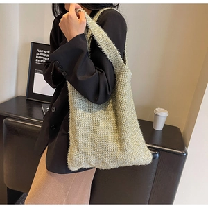 Golden knit tote bag with metallic texture shown on model in a minimalist setting