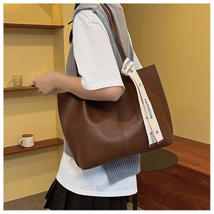 Detail of soft brown PU leather tote bag with a white fashion ribbon on the shoulder strap
