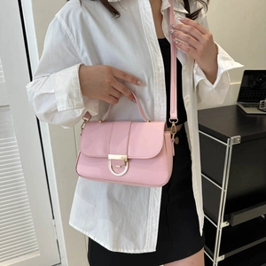 Pink faux leather crossbody handbag with gold clasp shown on model with white shirt