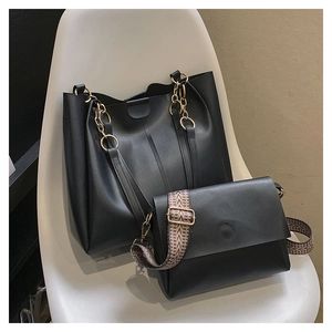 Detail of black tote set featuring gold chain handles and a woven chevron shoulder strap