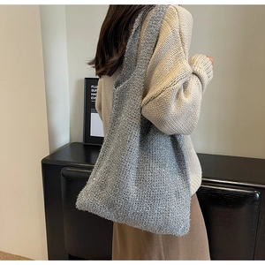 Detail of silver knitted tote bag showing metallic thread texture and wide shoulder strap