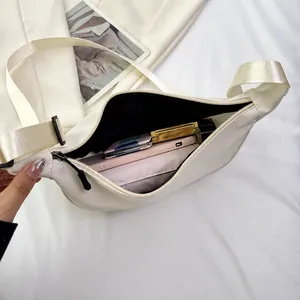 Dettaglio borsa a tracolla beige con scomparti interni e grande capacità di carico